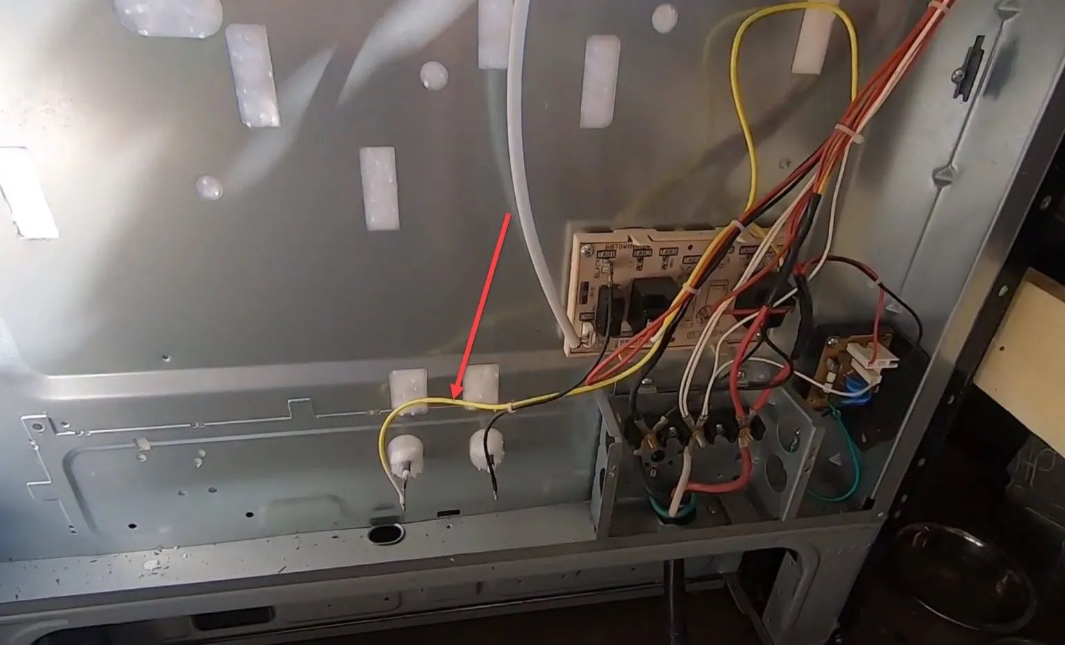 Interior of an oven with exposed wiring and components, including a control board, likely for repair.