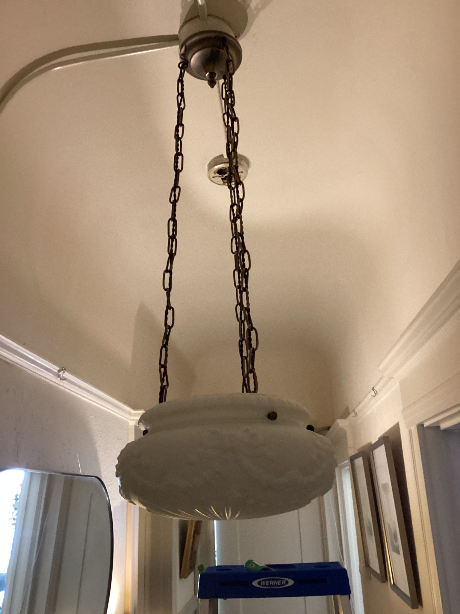 White glass pendant light fixture hanging from a ceiling, with decorative brown chains.