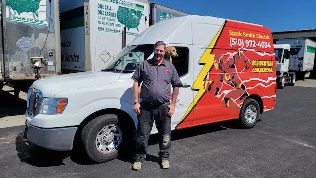 Man stands by a white and red utility van with an electrical company logo on the side.