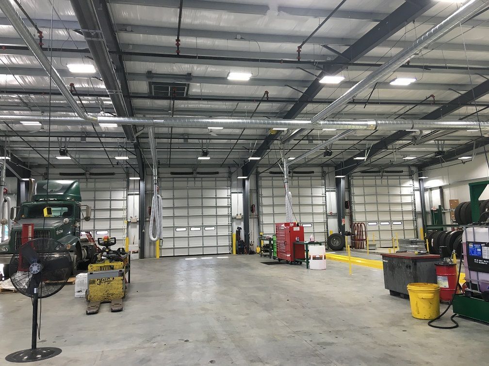 Interior of a large garage with multiple closed bay doors, equipment, and overhead lighting.