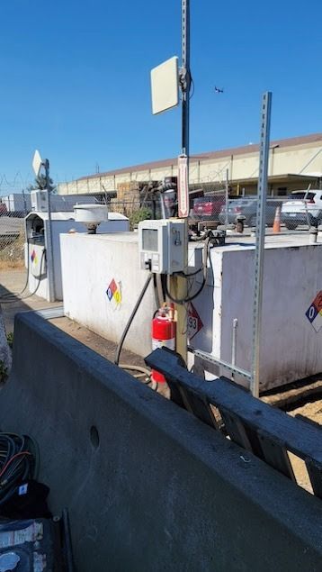 Fuel tanks with equipment and a communication tower, outdoors under a blue sky.