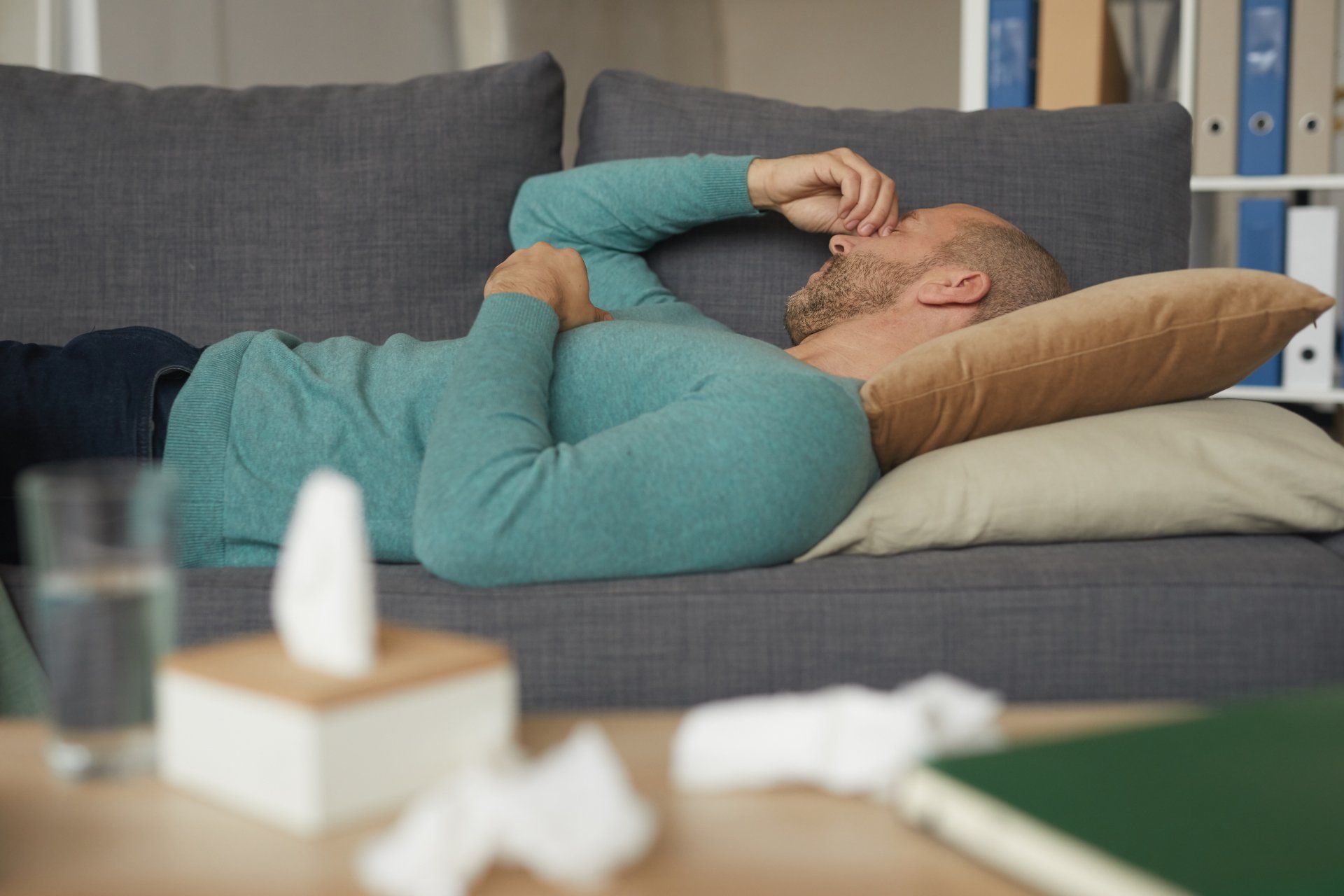 A man is laying on a couch with his head on a pillow.