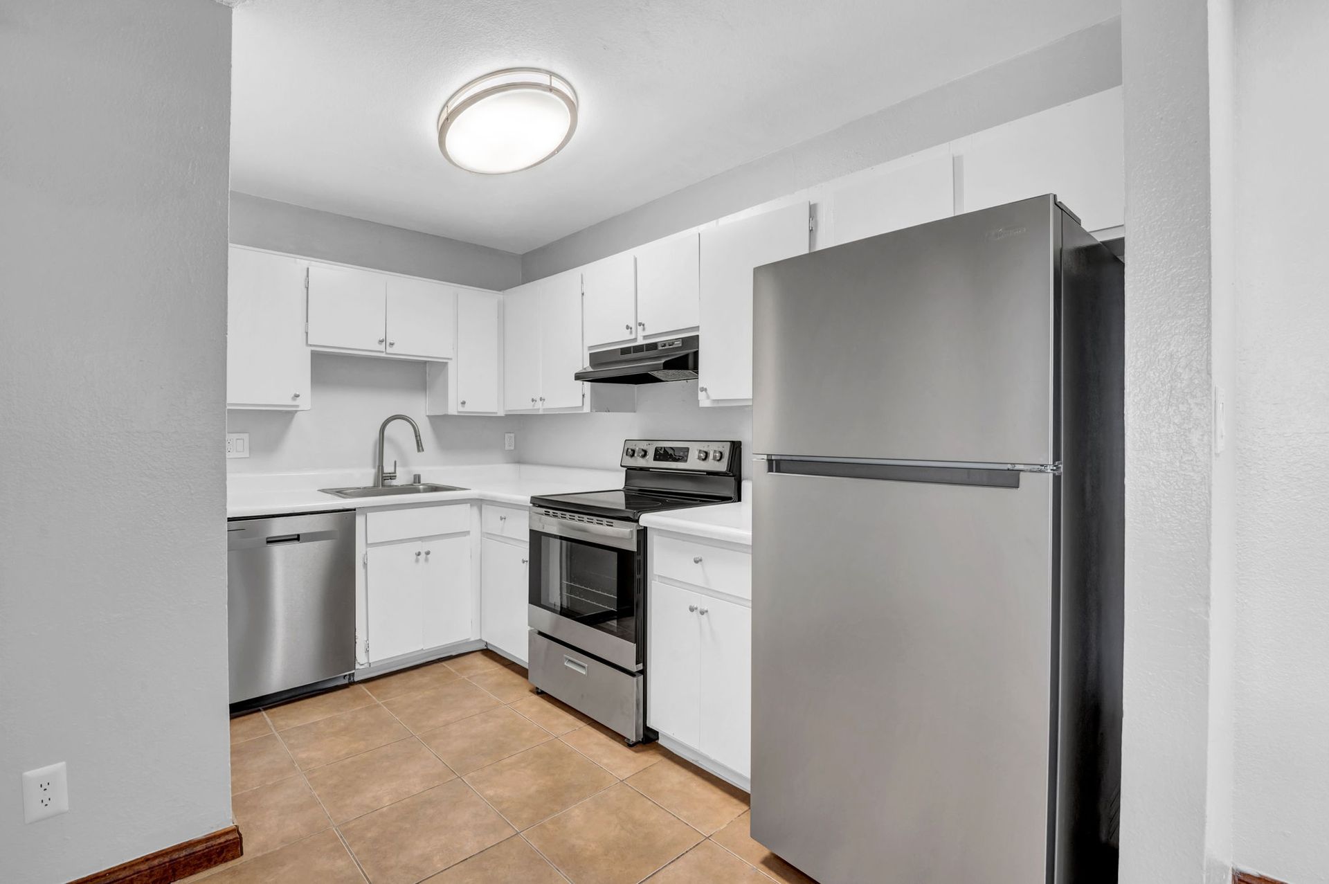 Image of a kitchen with white cabinets, and stainless steel appliances with silver hardware.