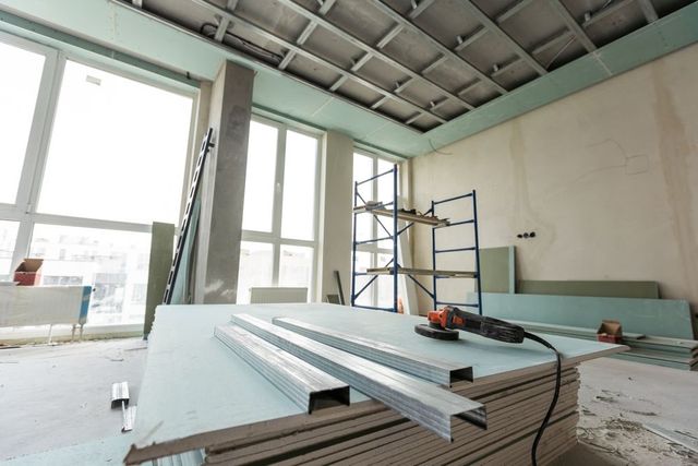 Interior construction site with drywall, metal studs, and tools.