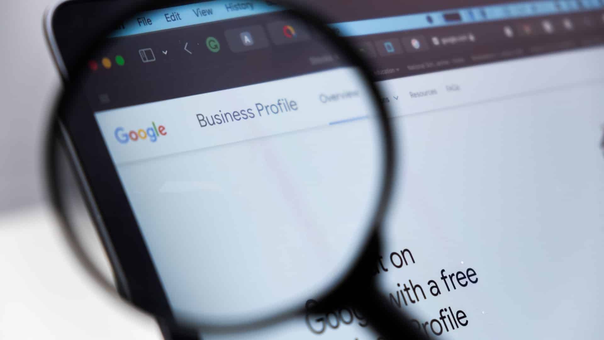 Magnifying glass over a laptop screen displaying the Google Business Profile webpage.