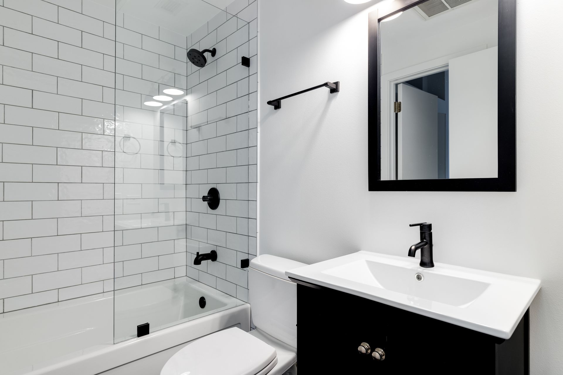 A bathroom with a toilet , sink , mirror and shower.