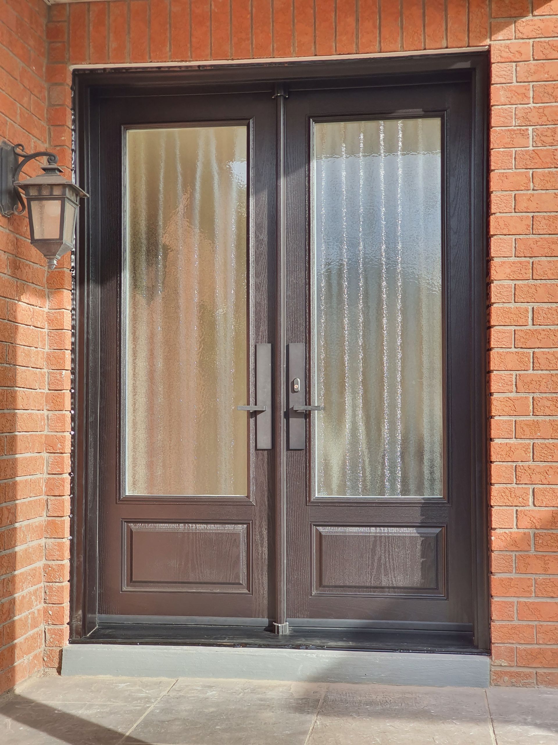 A brick building with a double door and a lamp on the side.