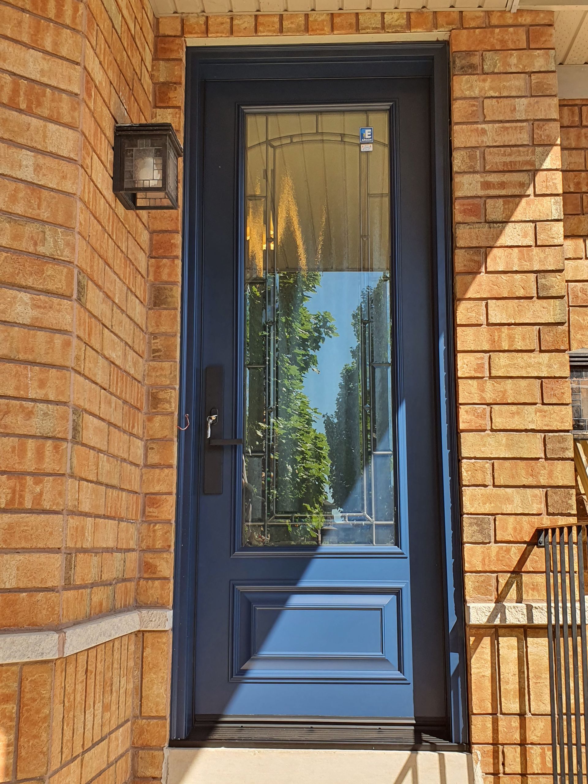 A blue door with a glass window is on a brick wall.