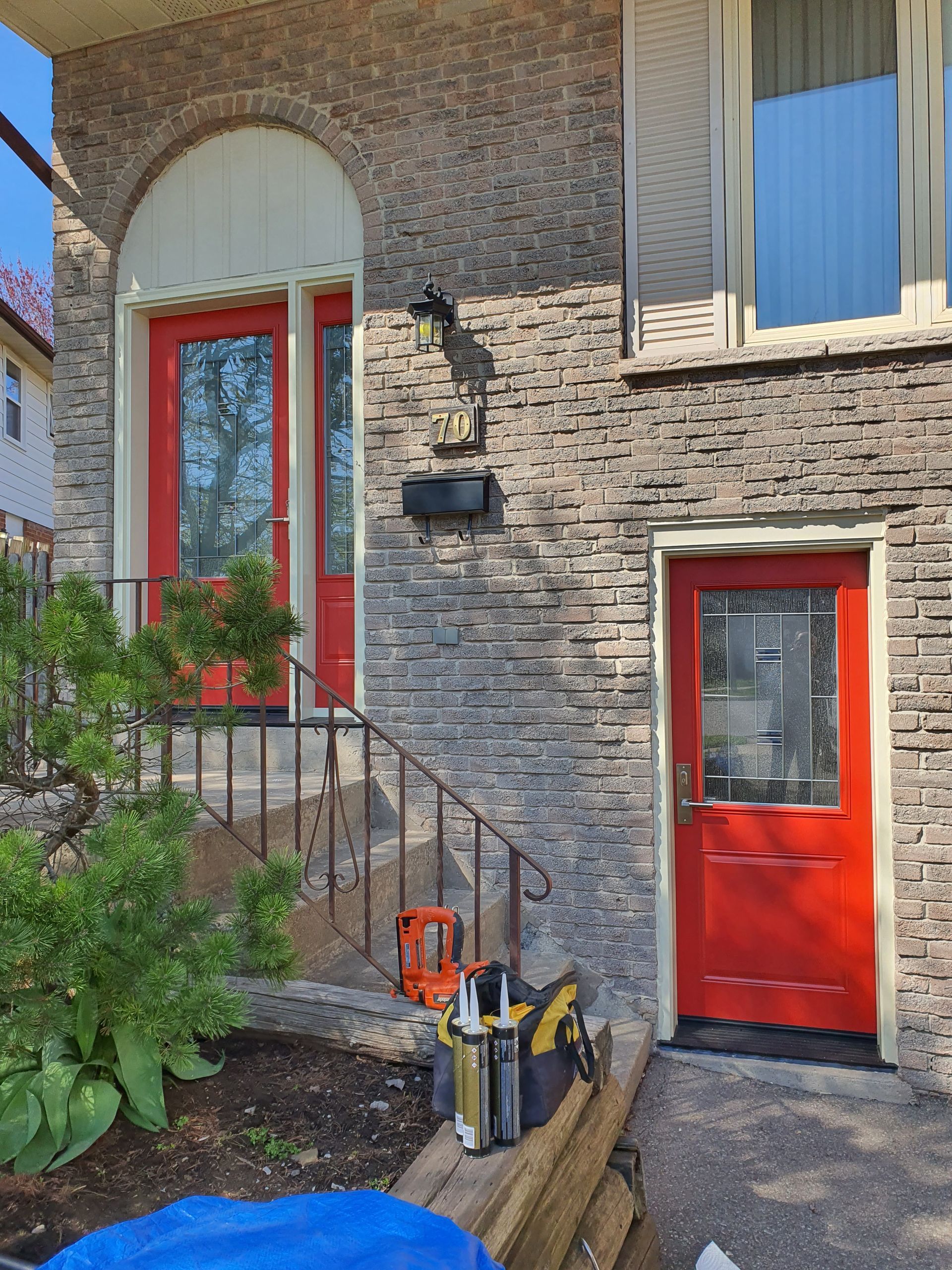 A red door is on the front of a brick house.