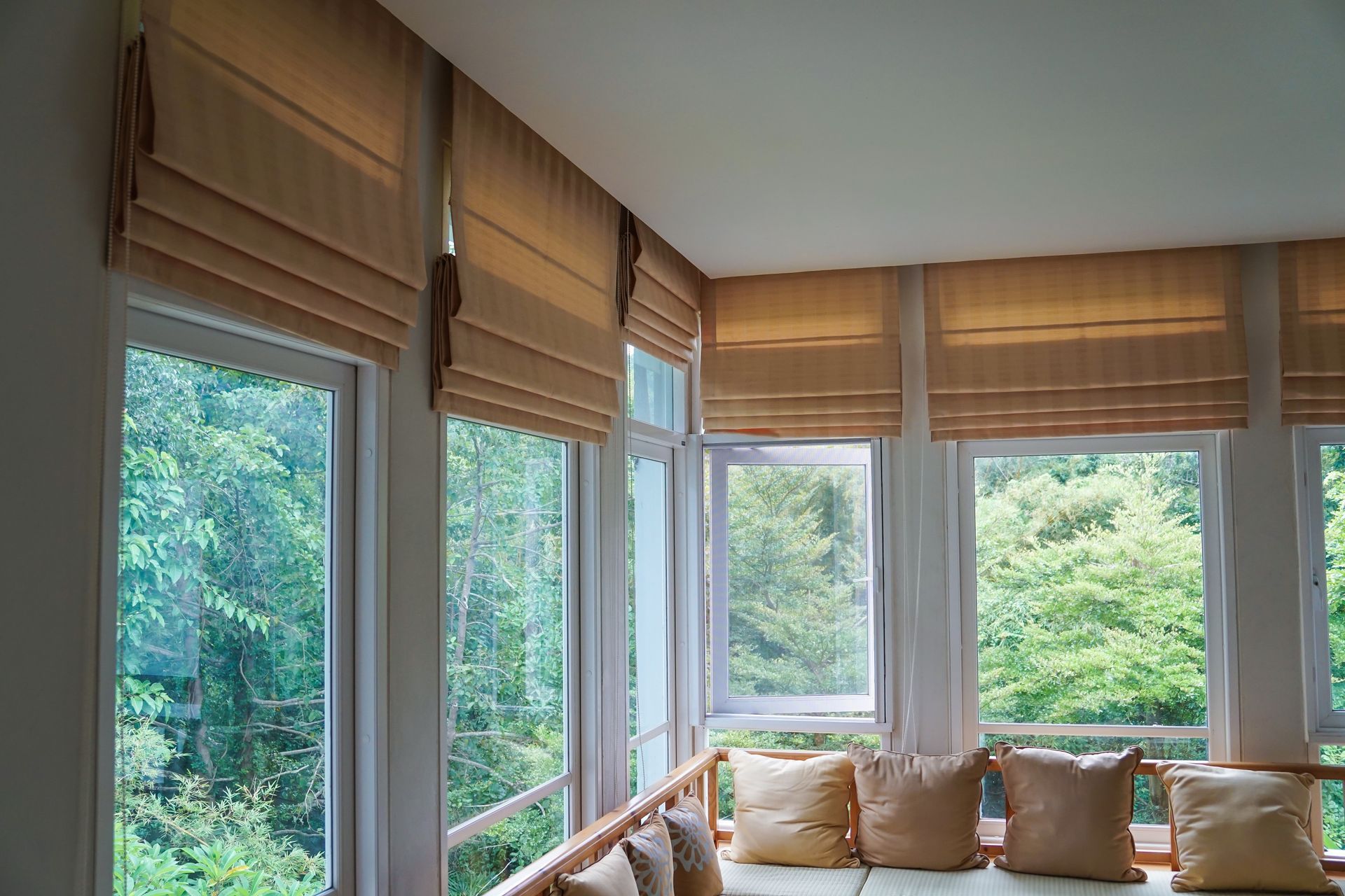 A living room with a couch and lots of windows with roman blinds.