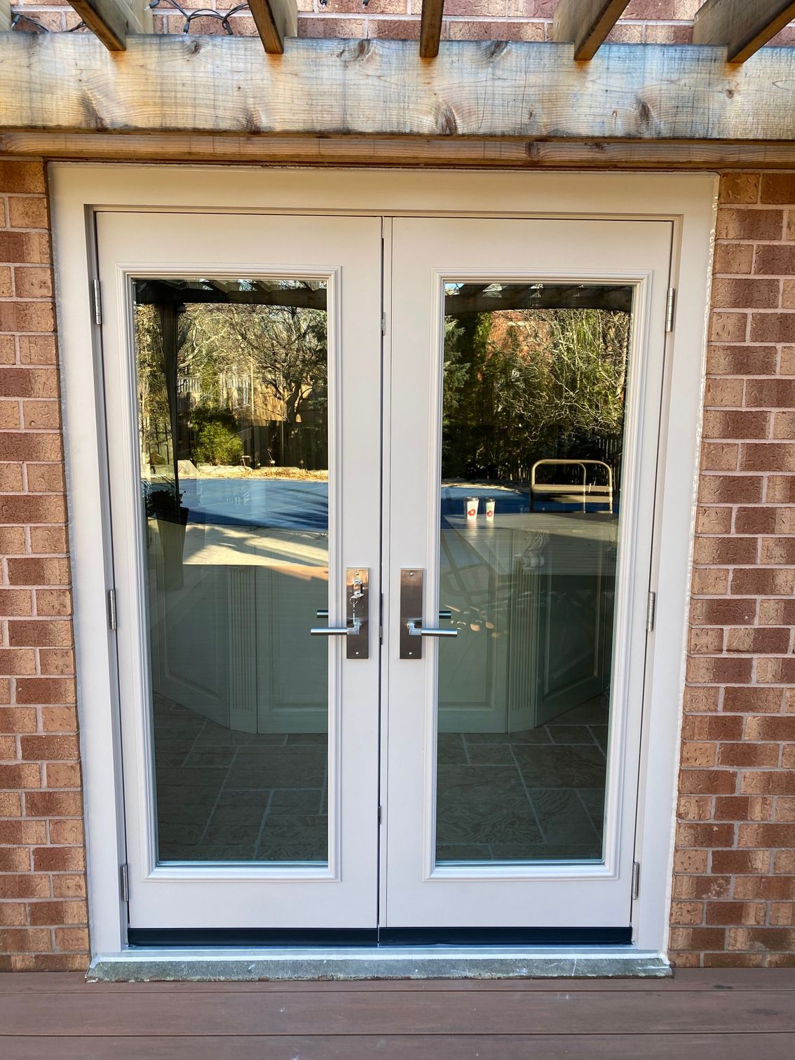 A pair of white french doors are sitting on top of a brick building.