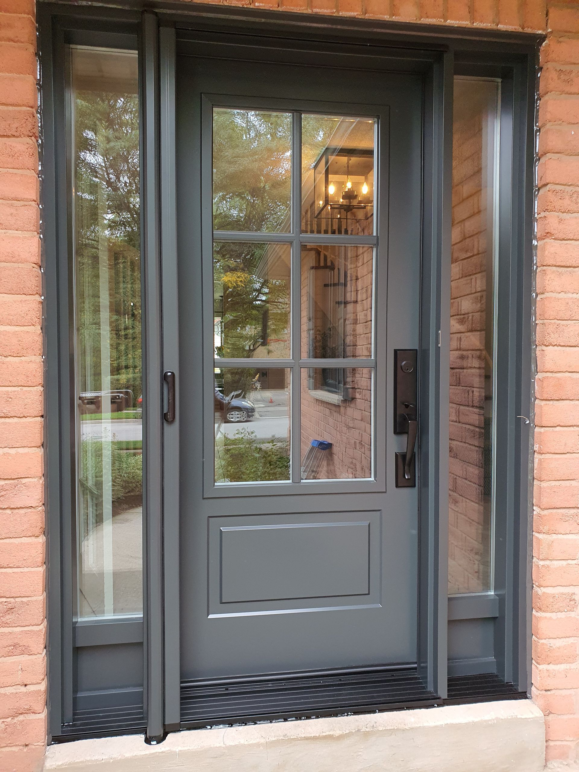 a gray front door with a brick wall behind it