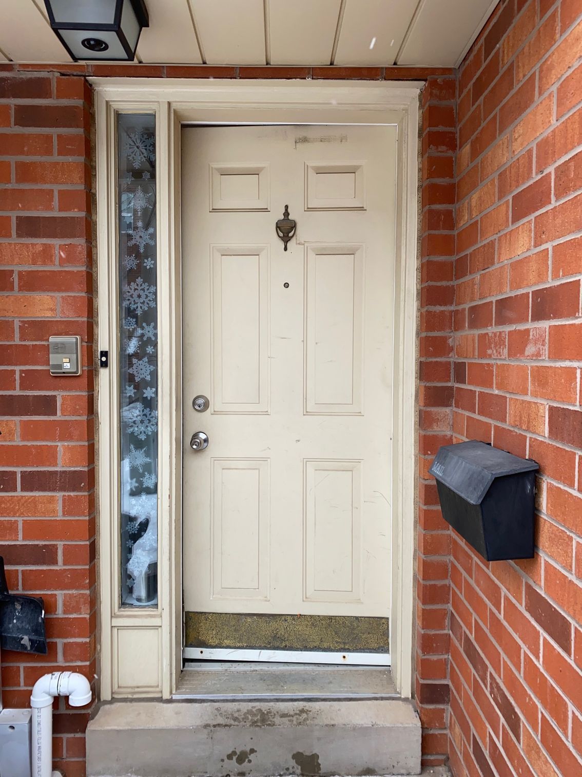 A brick wall with a white door and a black mailbox