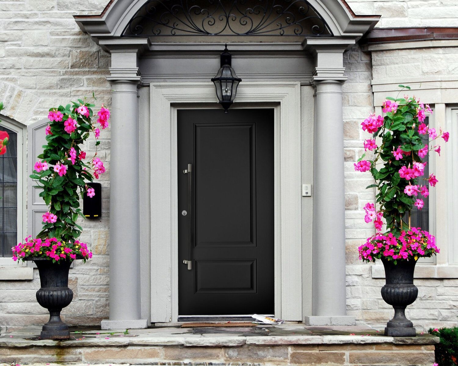 The front door of a house is decorated with pink flowers.