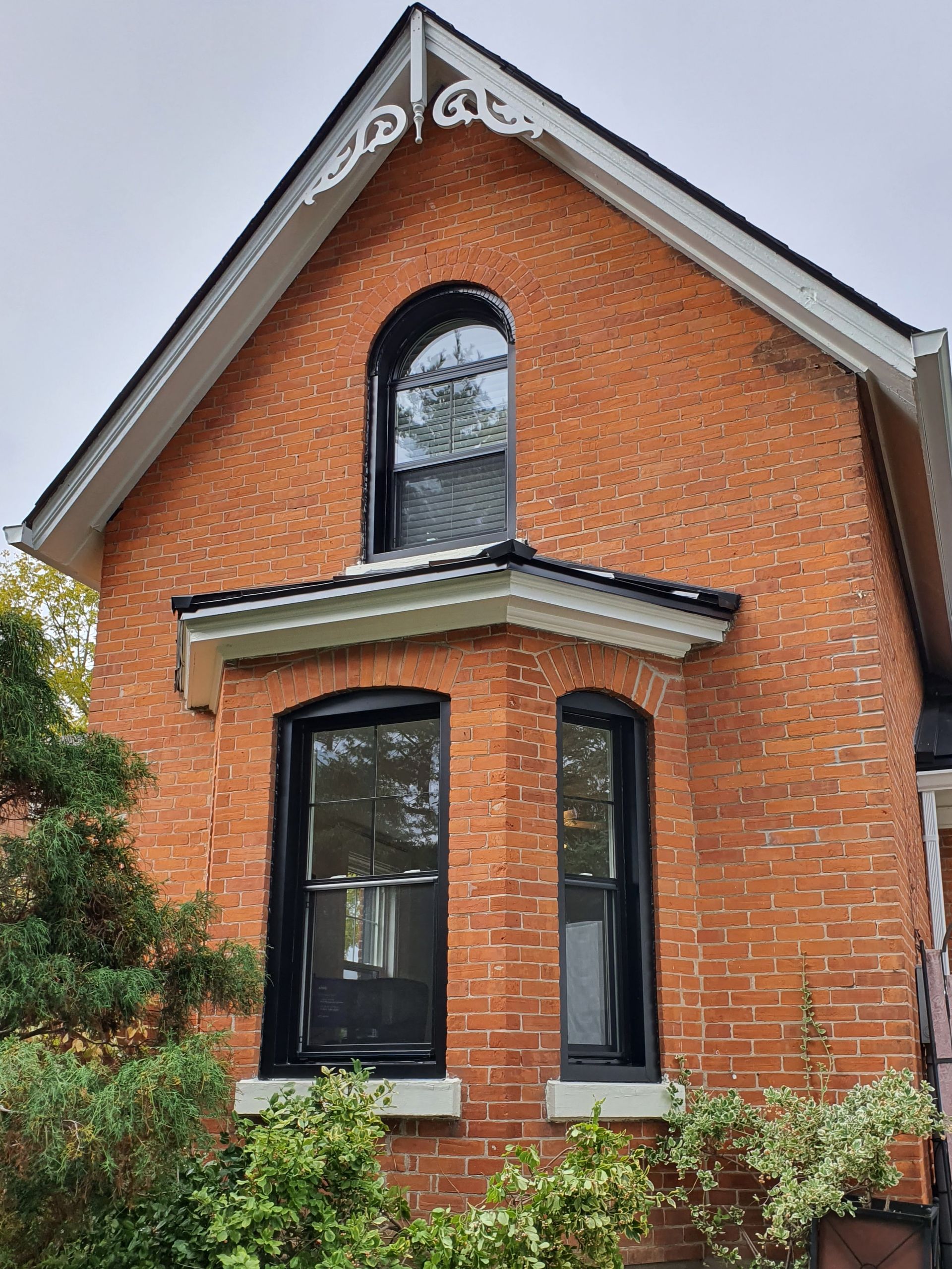 A brick house with black windows and a roof.