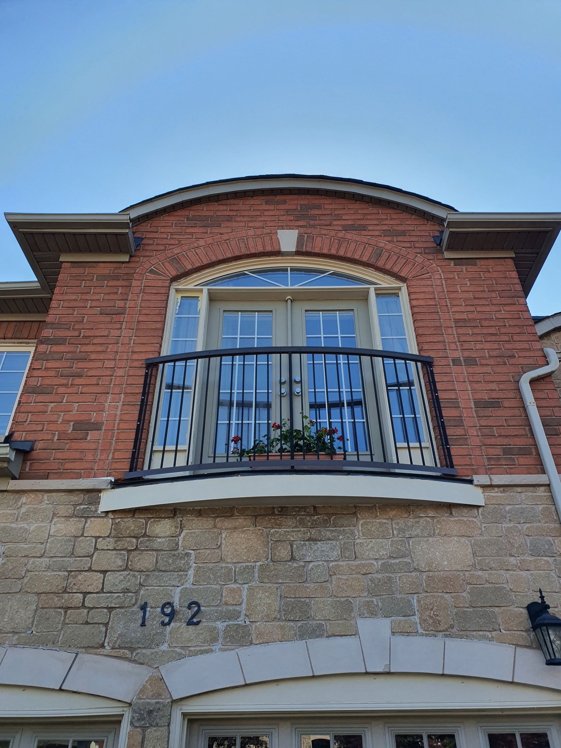 A brick house with a balcony on the top of it.