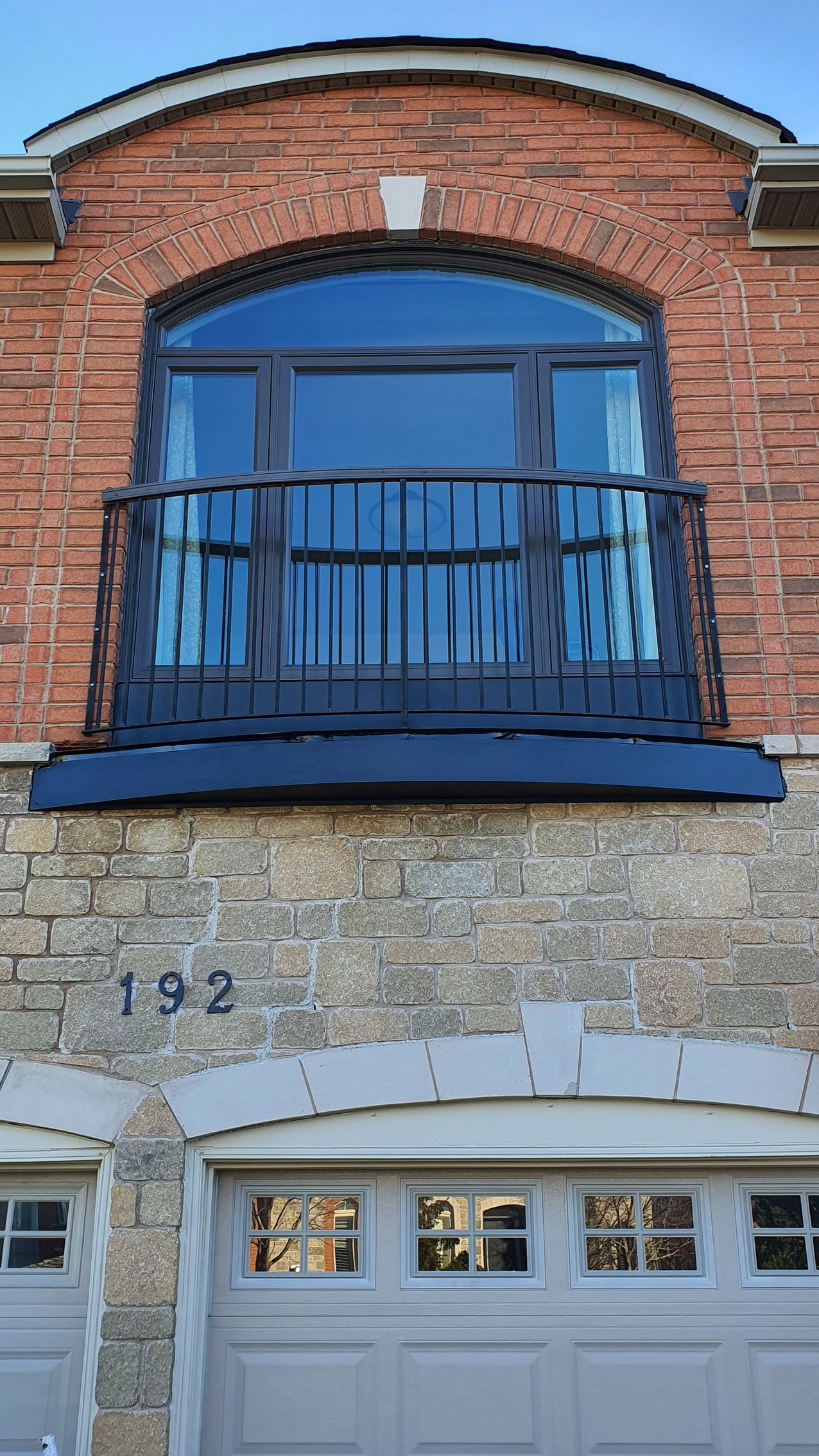 A brick building with a balcony and a garage door.