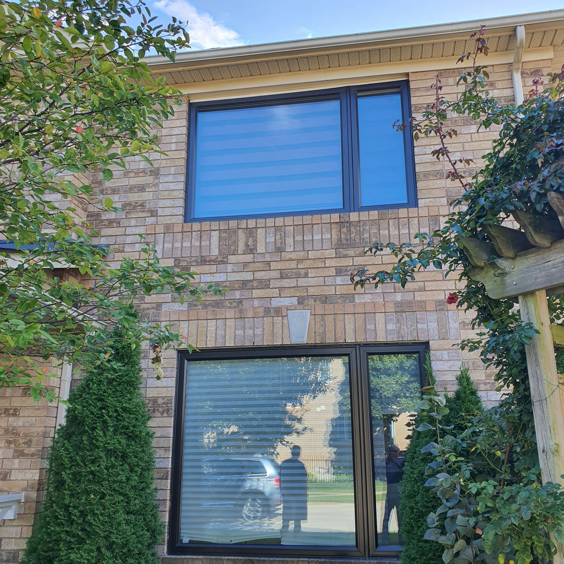 A brick house with a large window and trees in front of it