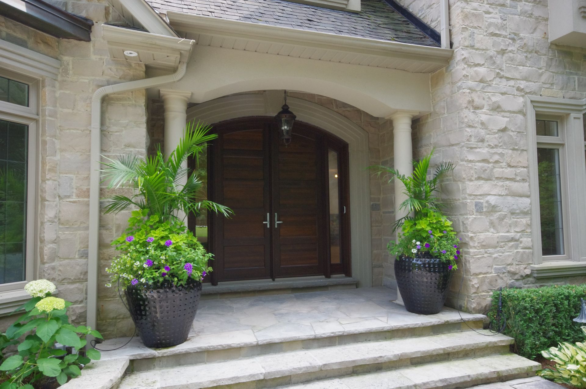 The front door of a house with potted plants in front of it.