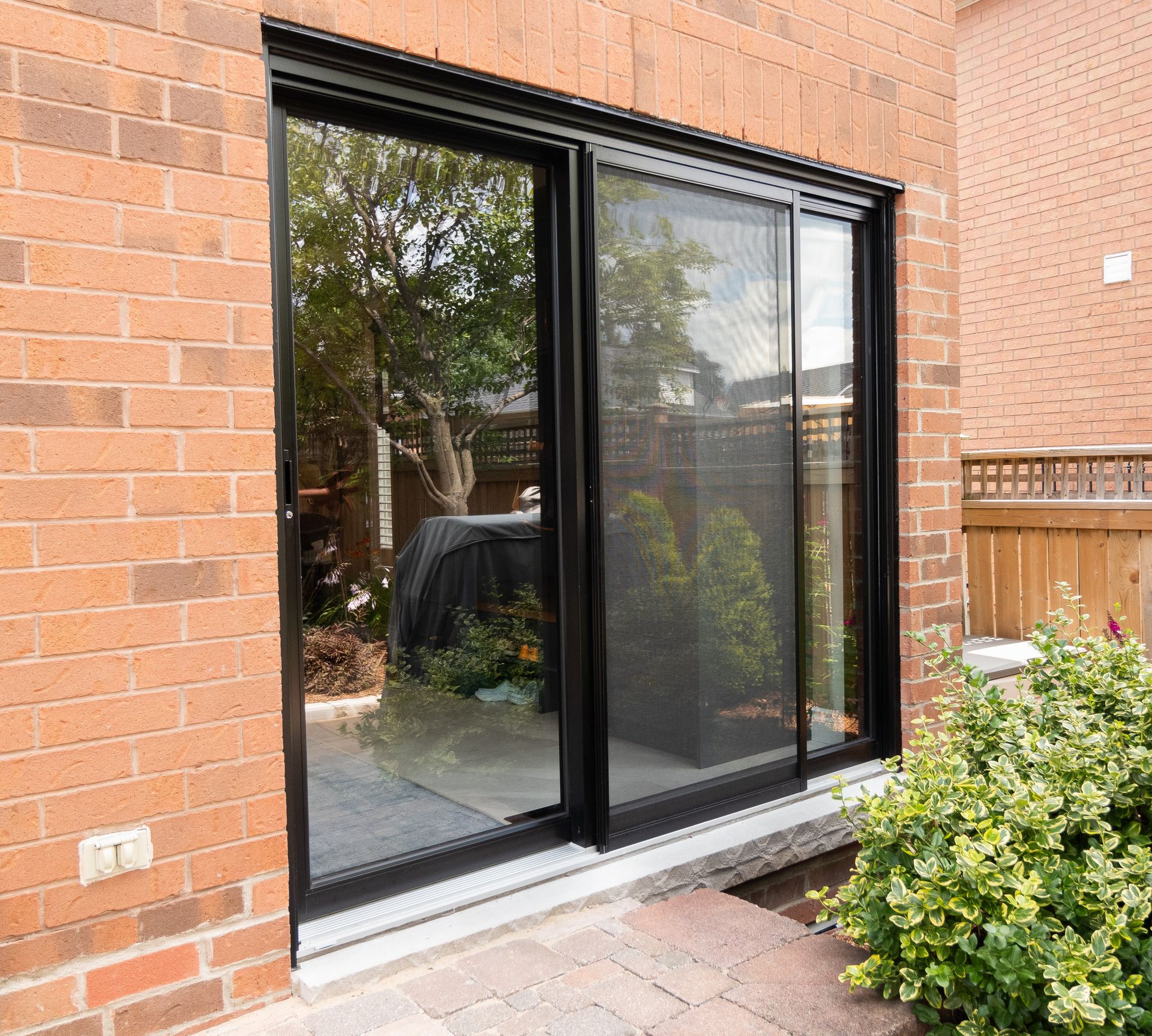 A brick building with a sliding glass door leading to a patio.