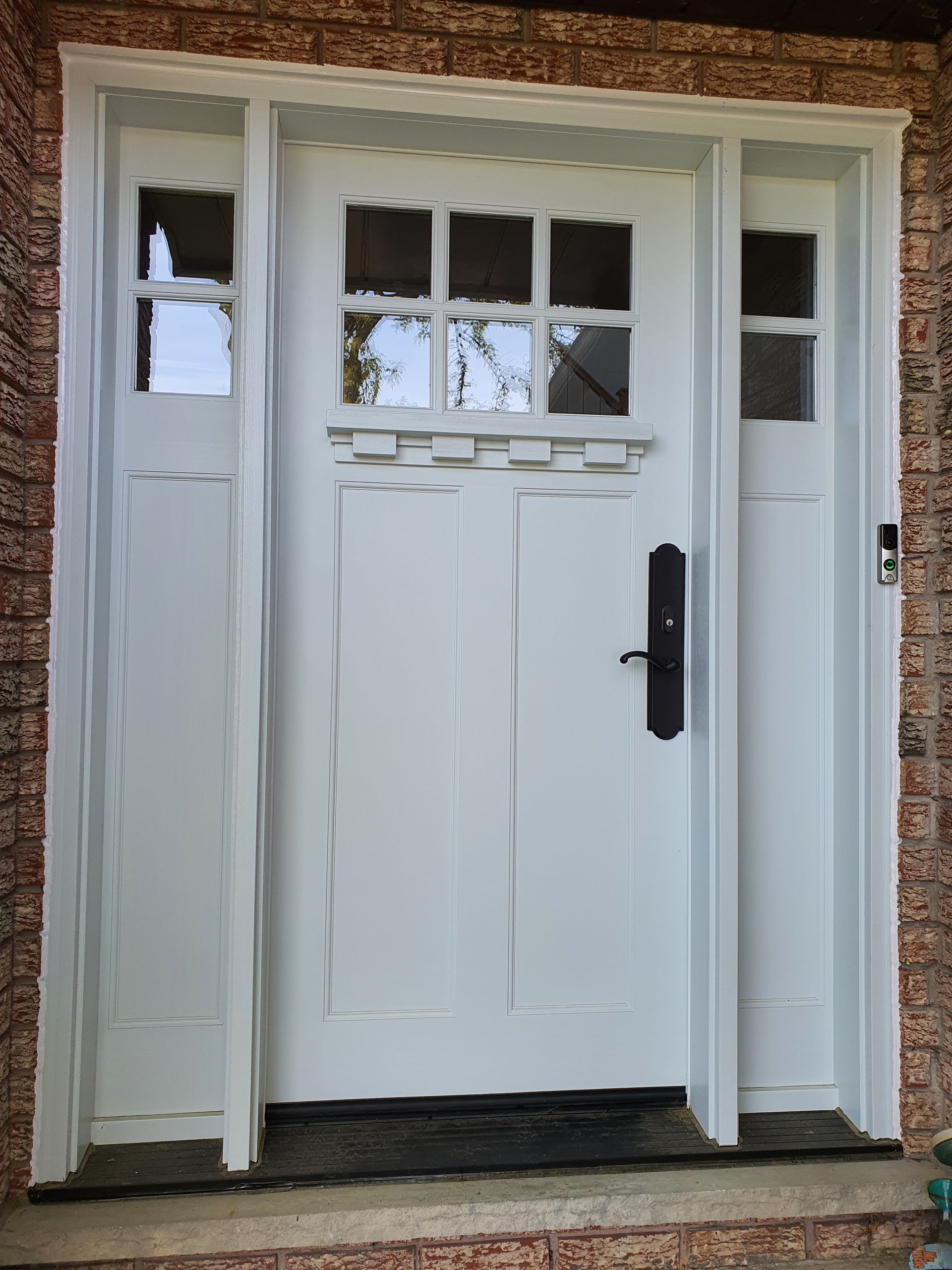 A white door with a black handle is on a brick wall.