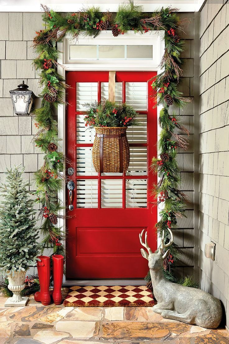 a red door decorated for christmas with a deer statue on the porch 