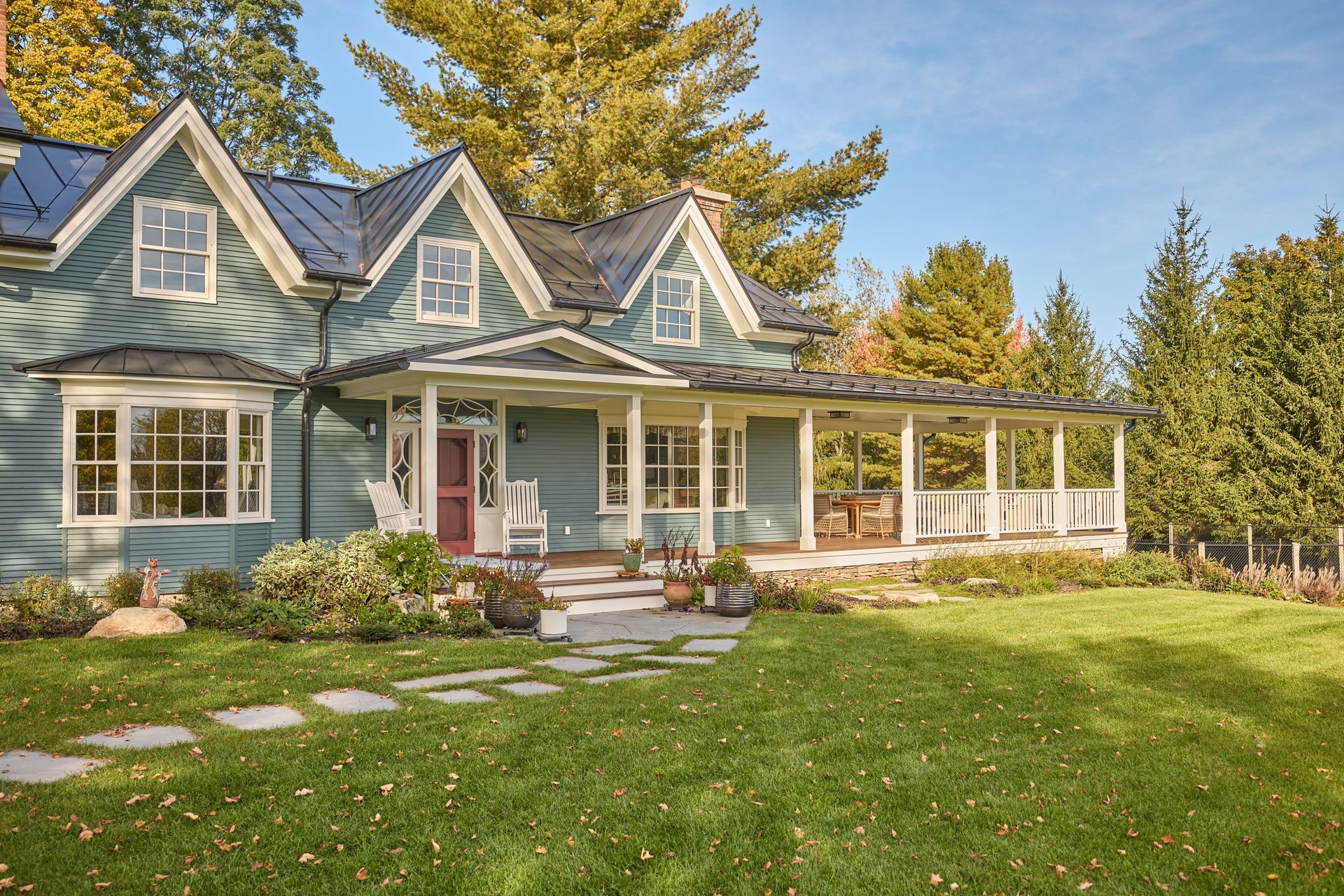 A large blue house with a large porch and a walkway leading to it.