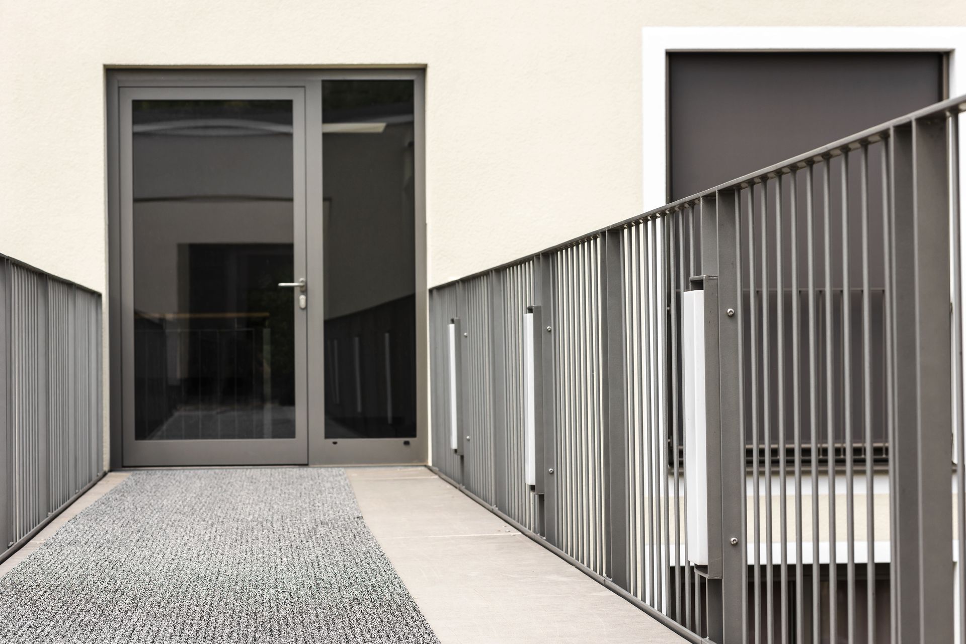 A staircase leading to a building with a glass door and a metal railing