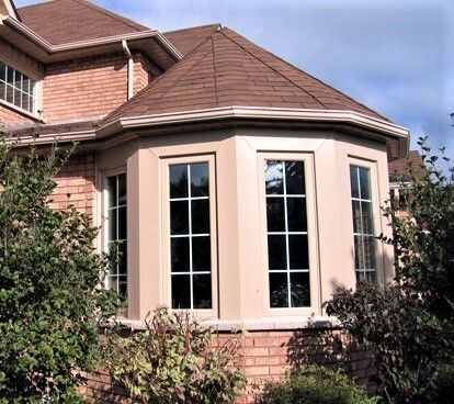 A brick house with a bay window and a brown roof
