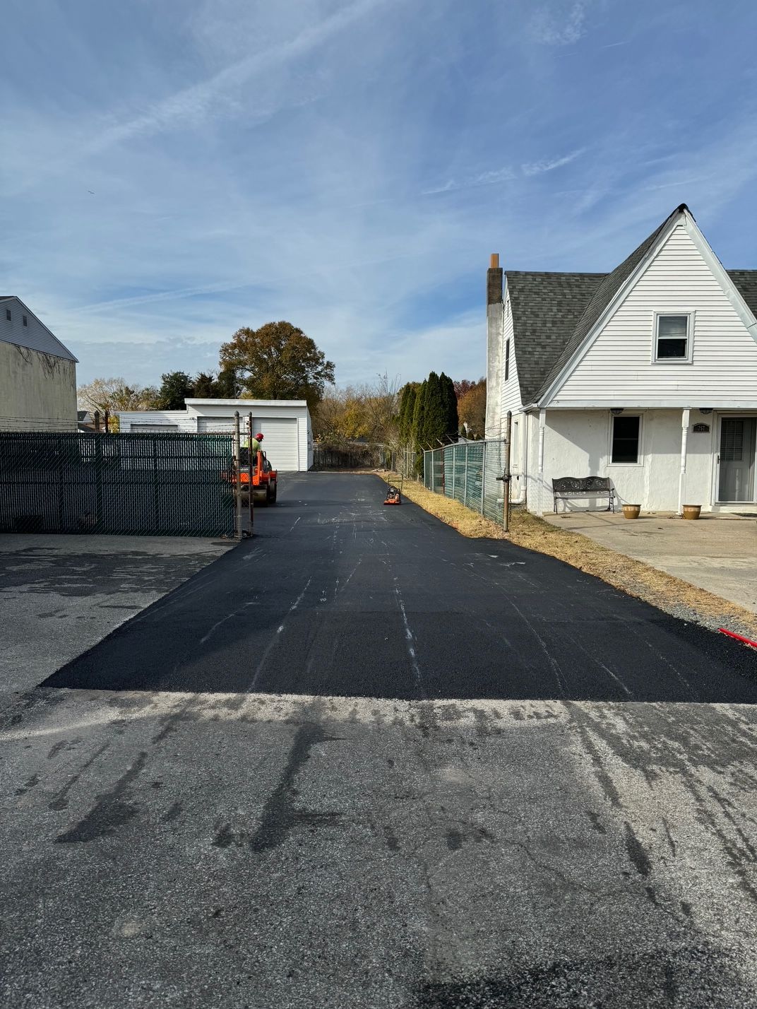 A Black Asphalt Driveway Leading to A White House.