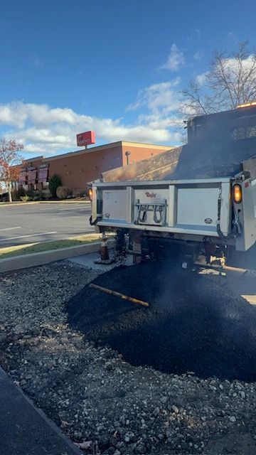 A Dump Truck Is Parked in A Parking Lot Next to A Building.