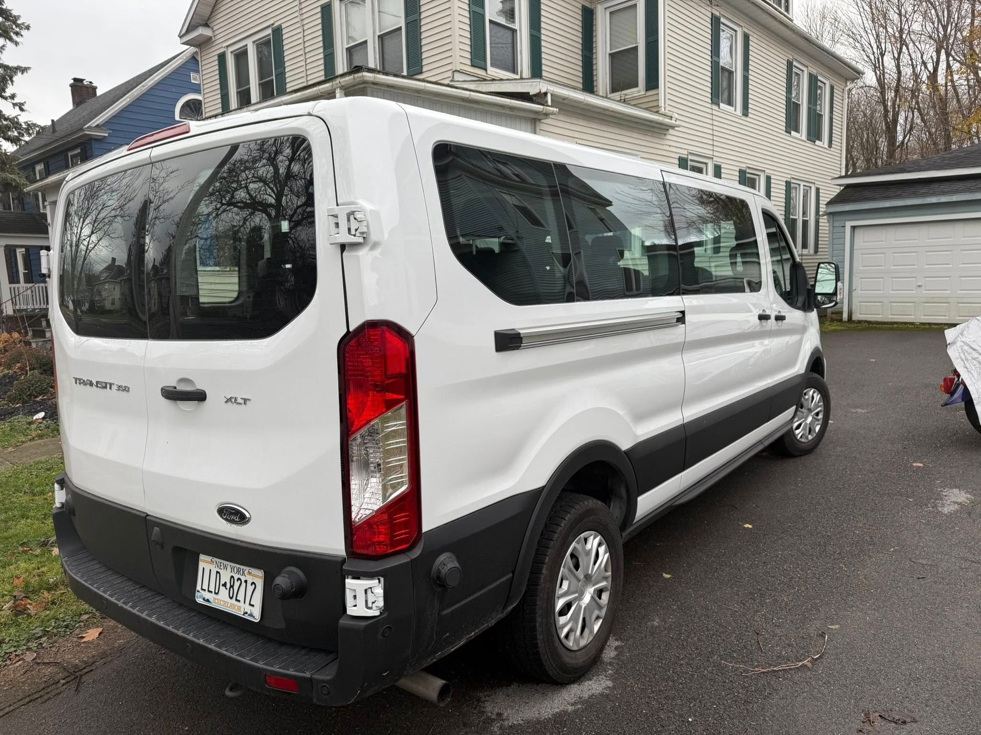 A white Ford Transit passenger van parked in a residential driveway.
