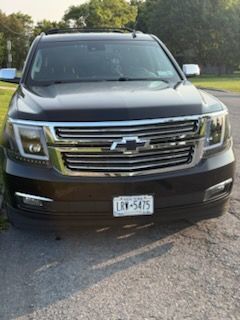 A black Chevrolet SUV parked on a paved road with a visible New York license plate.