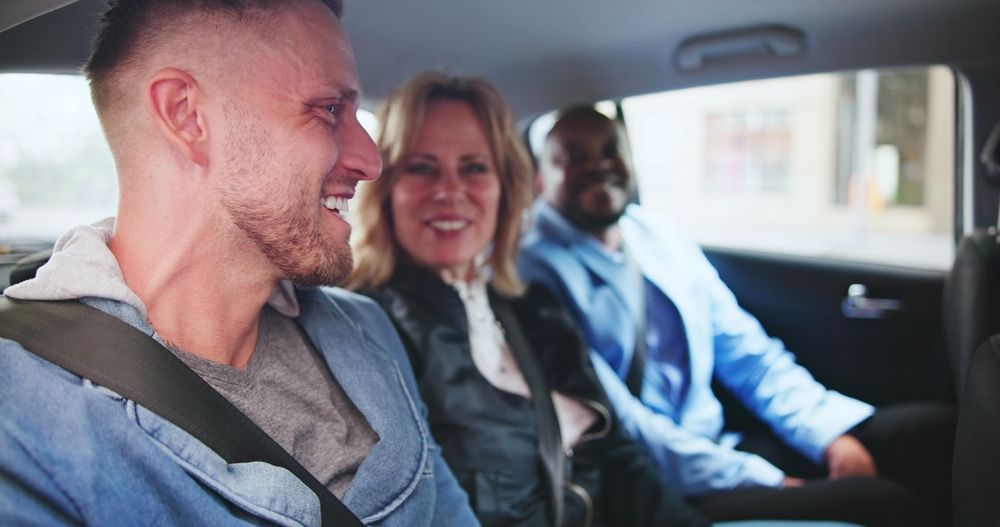Three people smile and talk while sitting in the back seat of a car.