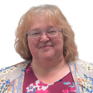 Woman with glasses, short auburn hair, smiling, wearing a floral shirt. White background.