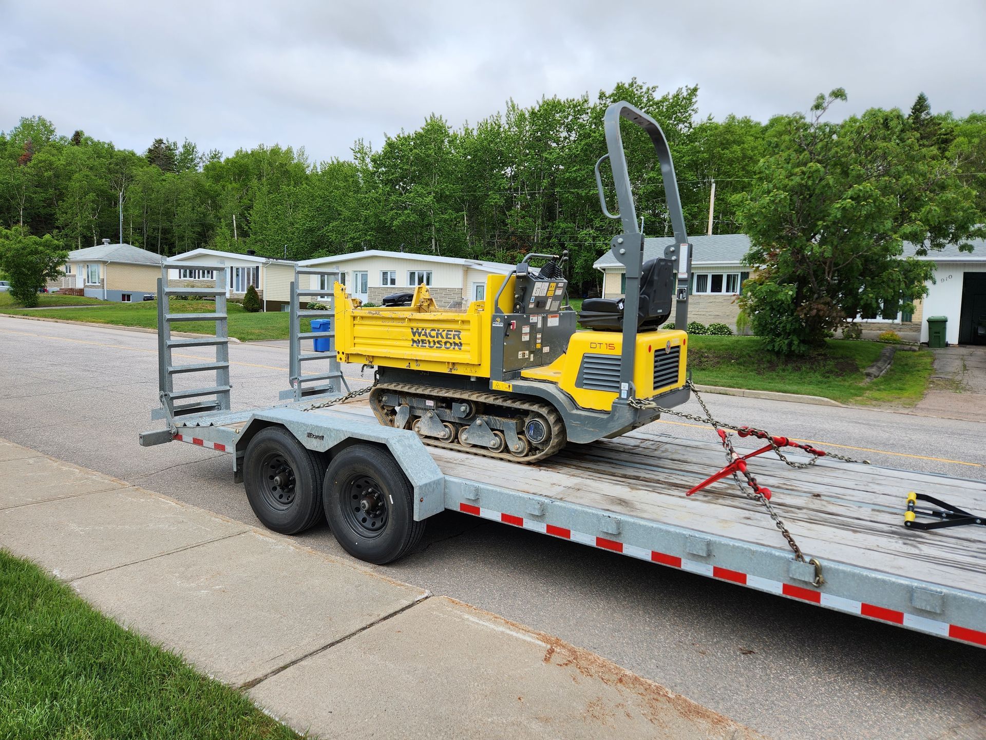Un petit camion à benne jaune est assis sur une remorque.