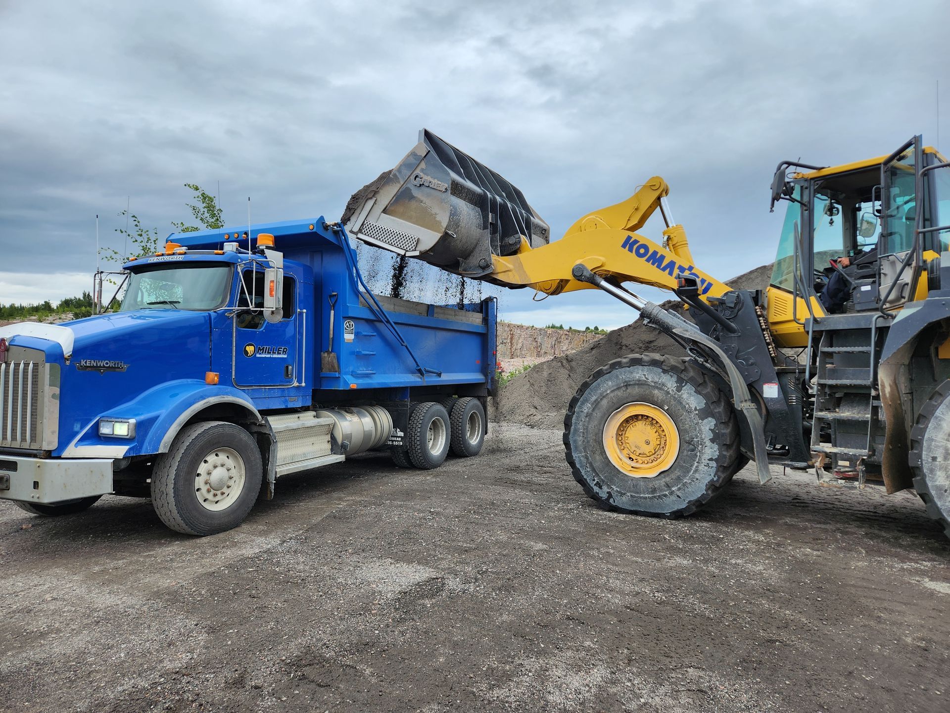 Un camion à benne basculante est chargé de terre par un bulldozer.