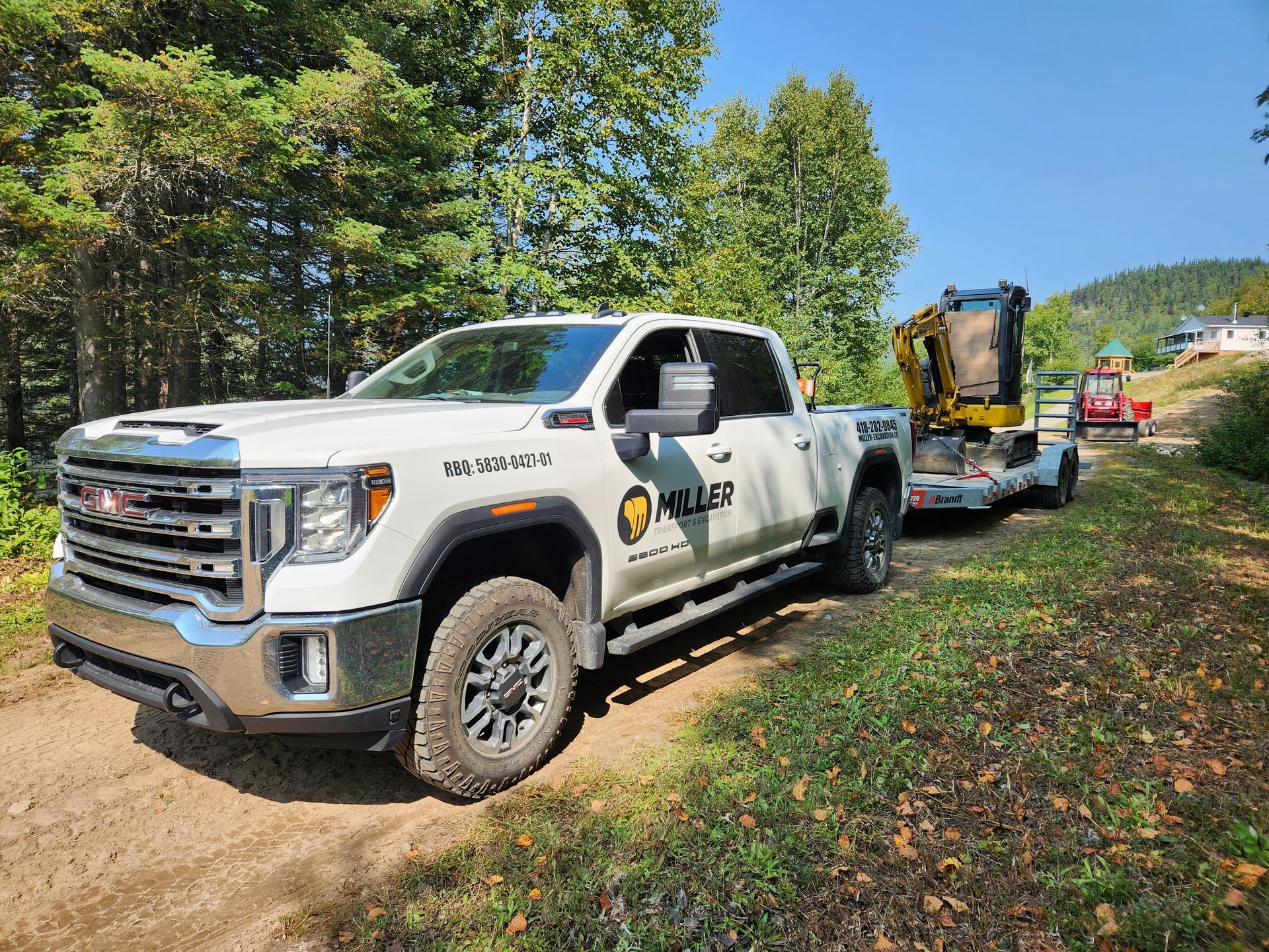 Un camion blanc est garé sur un chemin de terre à côté d'une remorque.