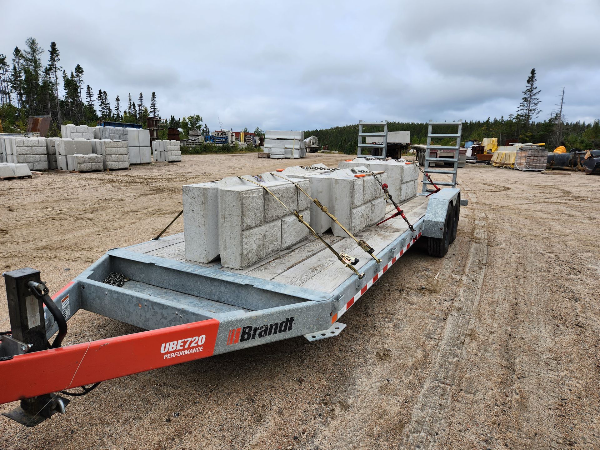 Une remorque avec des blocs de béton dessus est garée dans un champ de terre.