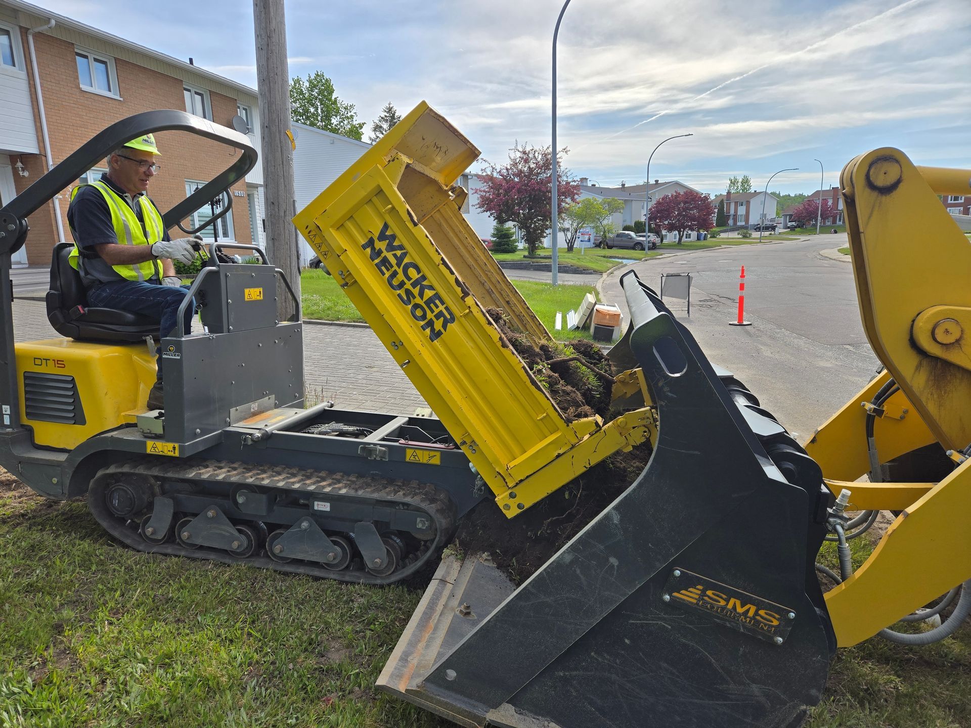 Un homme conduit un camion-benne jaune avec la porte arrière ouverte.