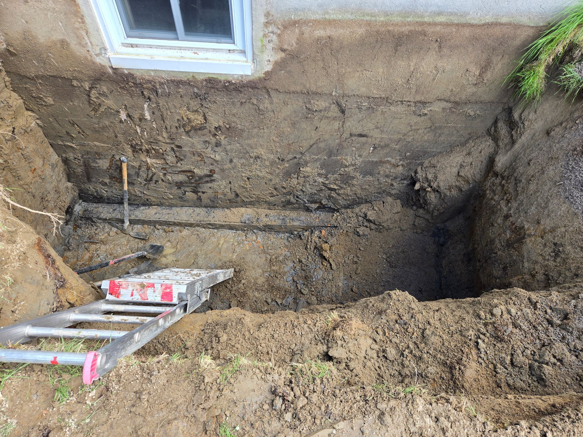 Une échelle est posée dans la terre à côté d'un trou dans le sol.