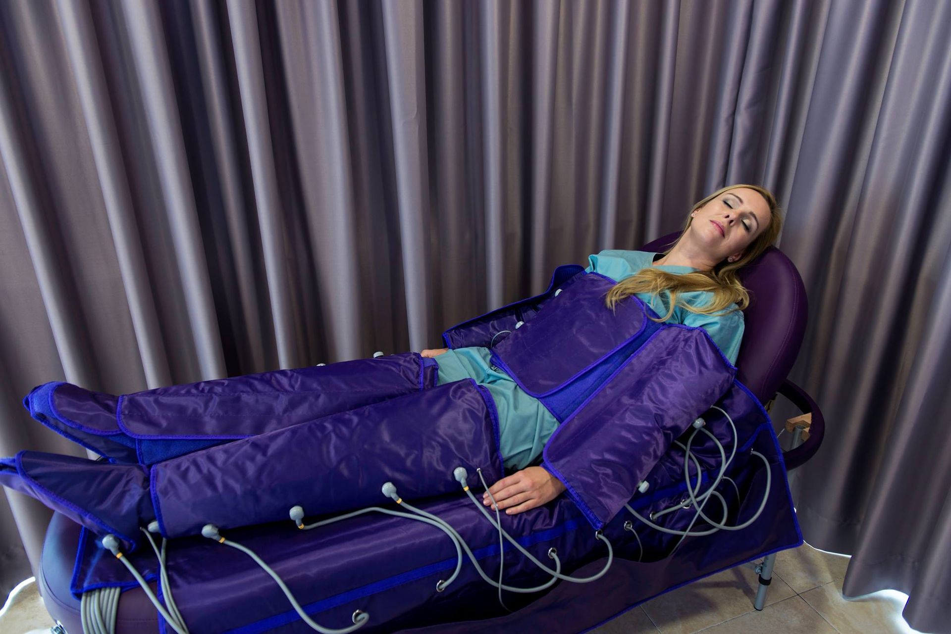 A woman is laying on a couch getting a lymphatic drainage treatment.