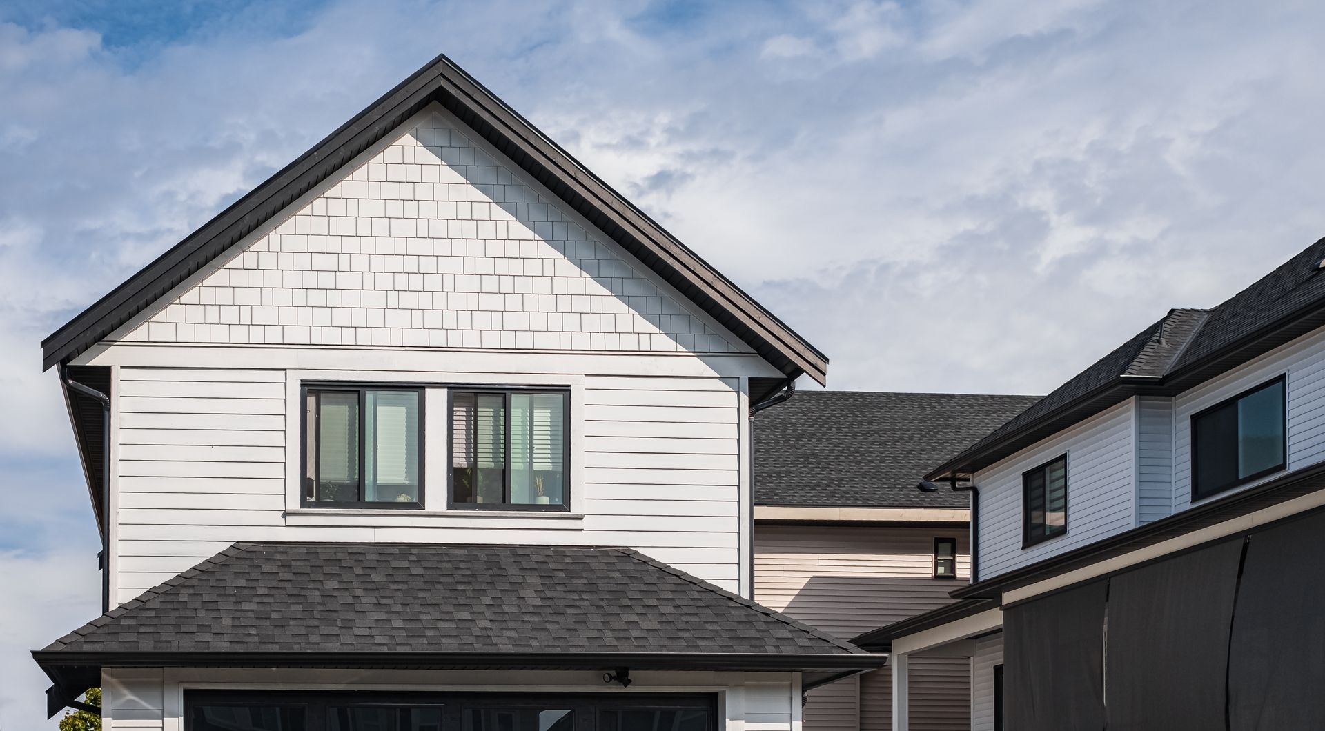 A white house with a black roof and a black garage door.