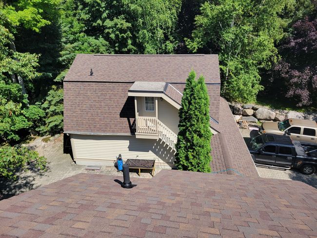 An aerial view of a house with a roof that is surrounded by trees.