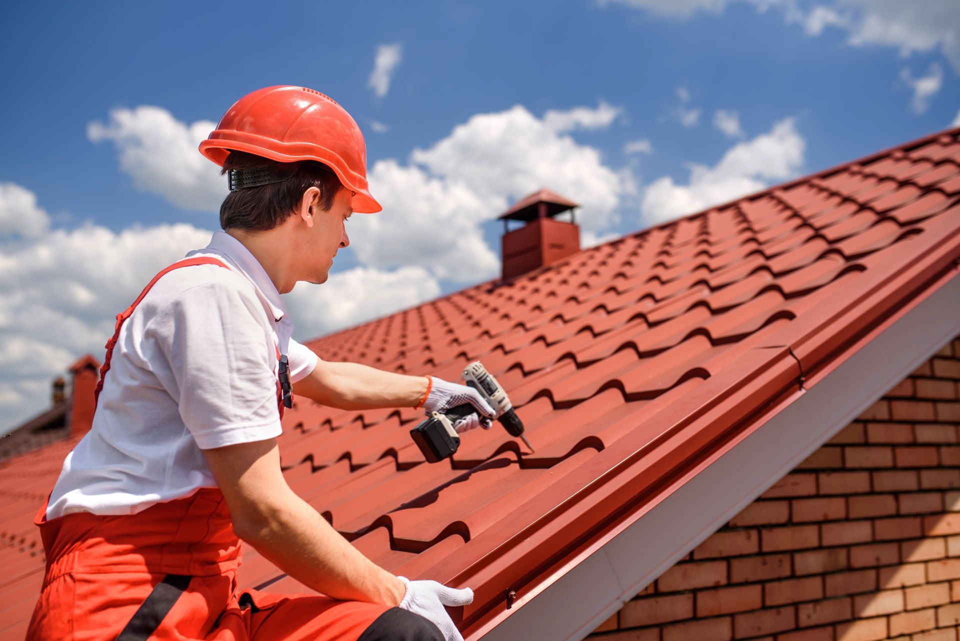 A man is working on a roof with a drill.