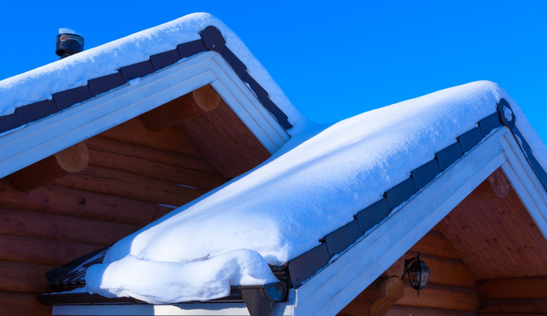 The roof of a log cabin is covered in snow.