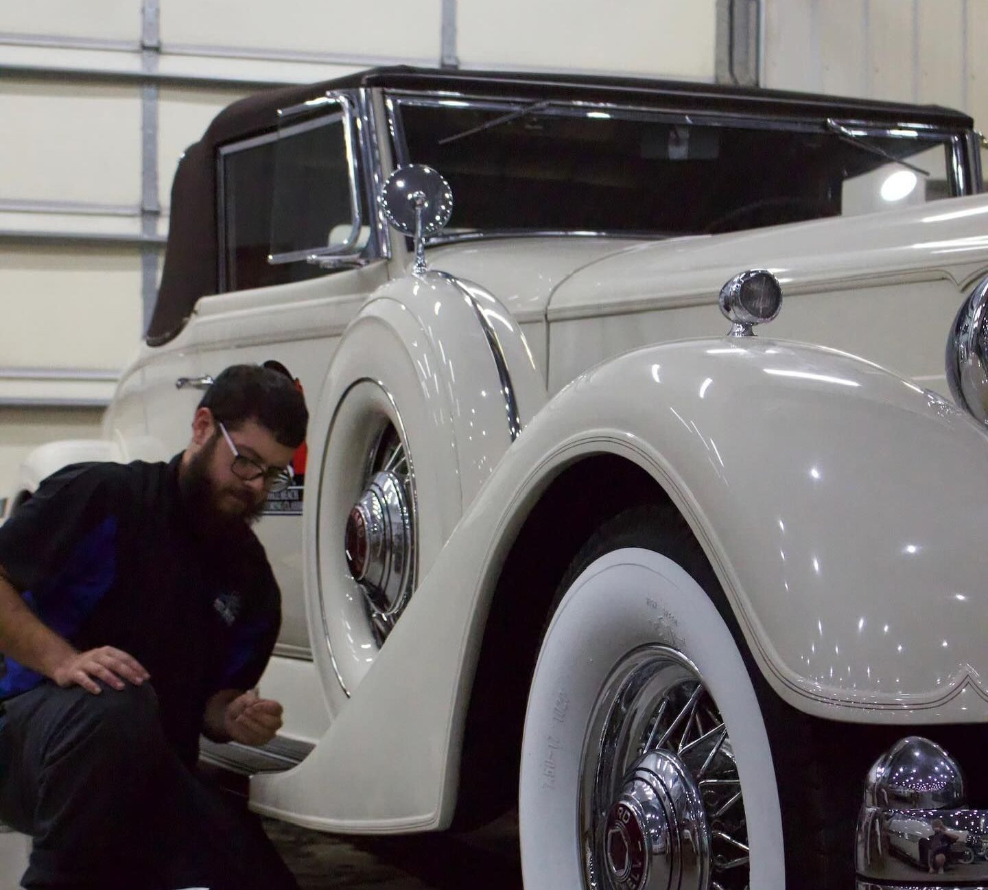 A man is working on a white car in a garage