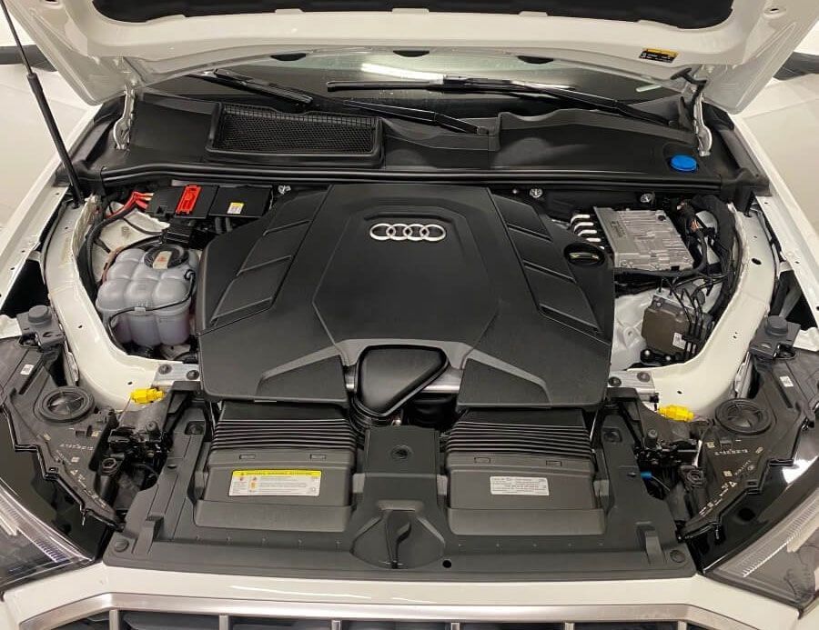 The engine of a white audi q7 is shown with the hood open.