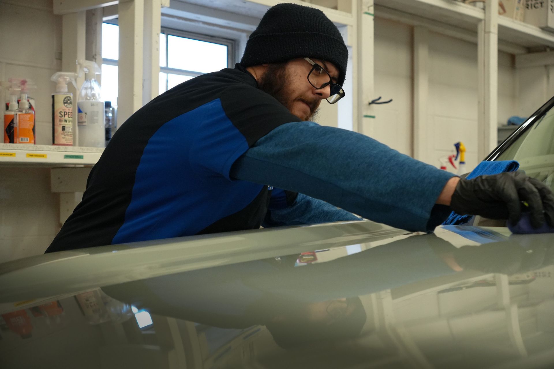 A man with a beard is applying a coating to a car.