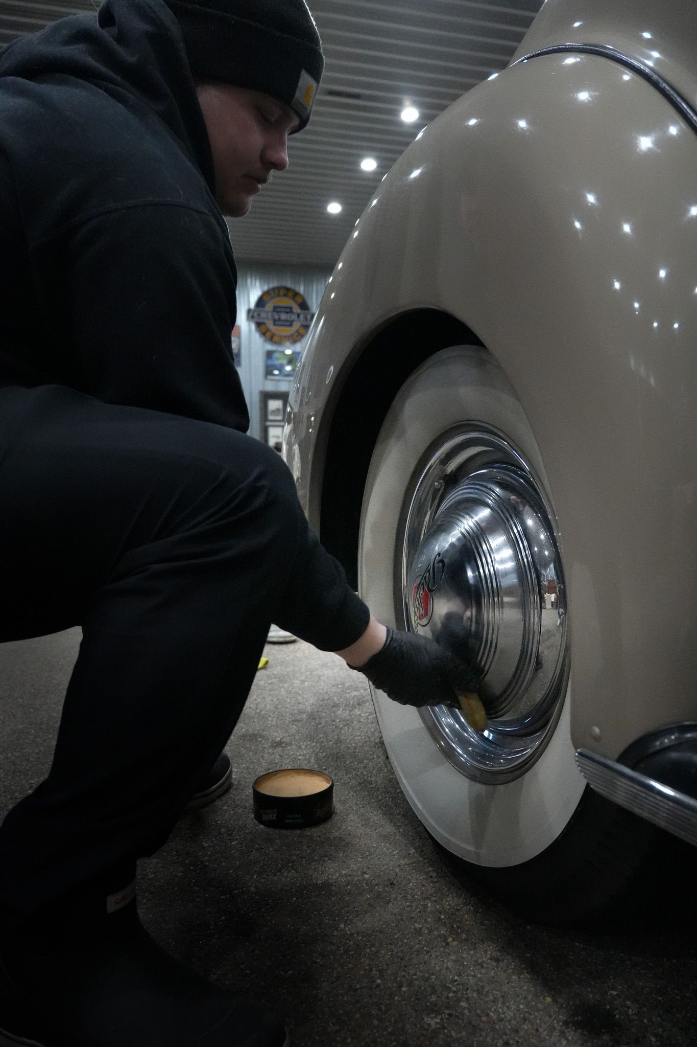A man is cleaning a car wheel with a brush.